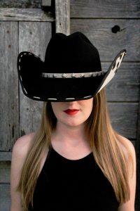 Bonnie Sims of Everybody Loves an Outlaw poses in a hat. | Natalie Jo Gray
